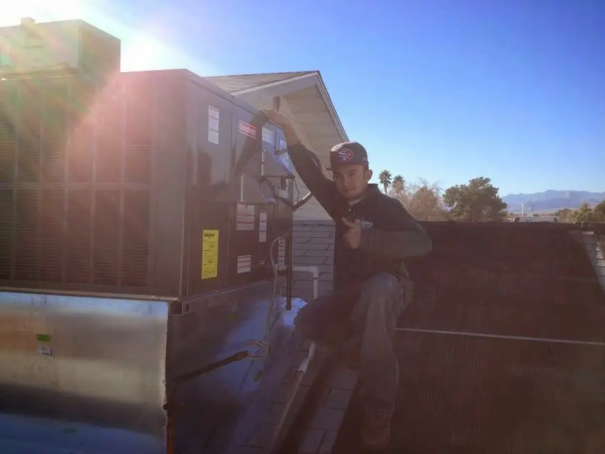 HVAC technician performing Air Duct Cleaning on a rooftop unit in Reading